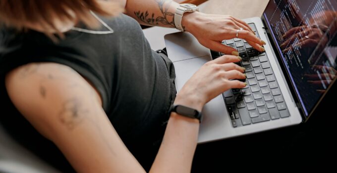 Close up of young woman programmer writes program code on laptop while sitting in modern coworking